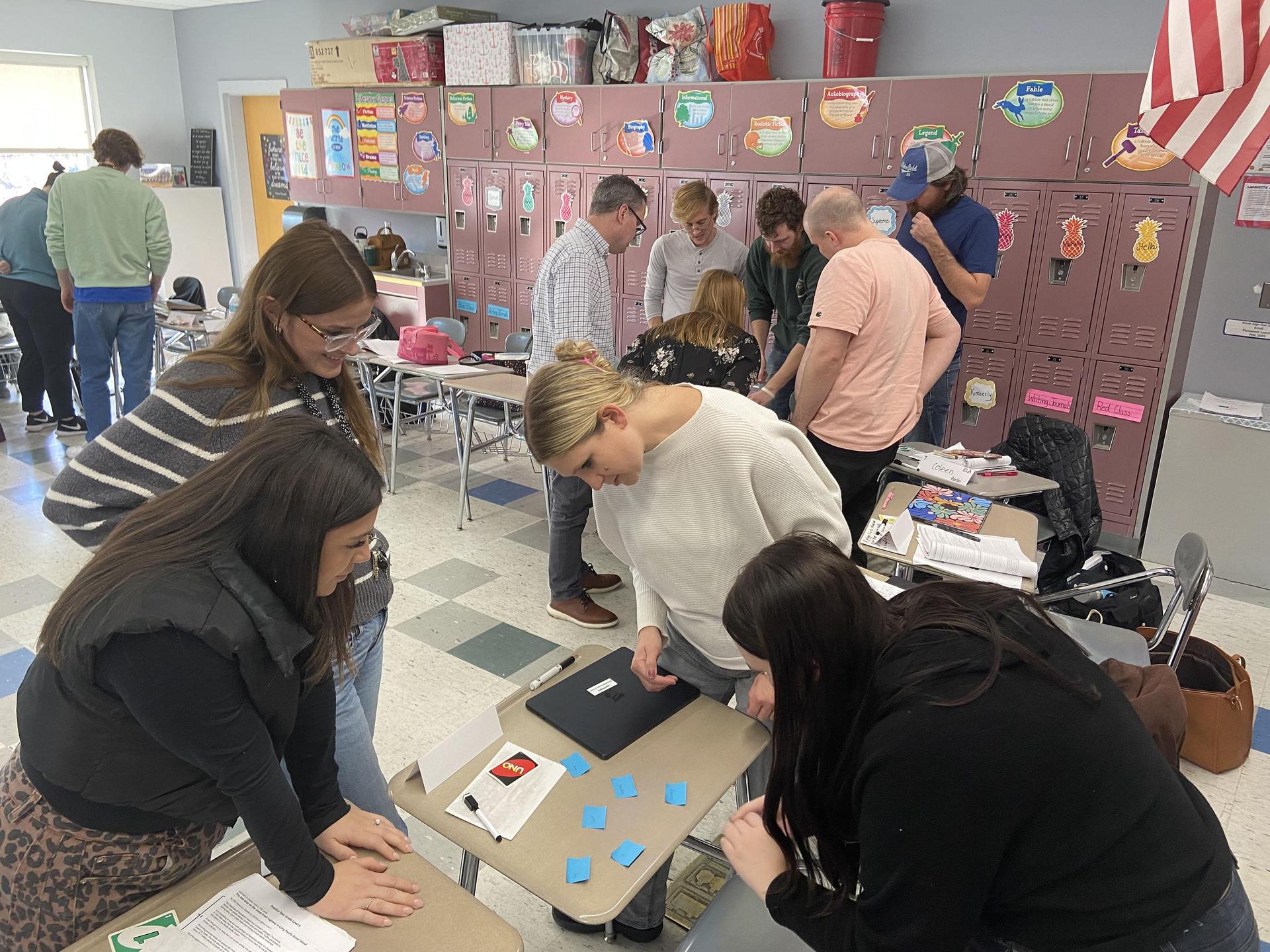 People collaborating in a classroom, engaging in discussions and activities around tables.