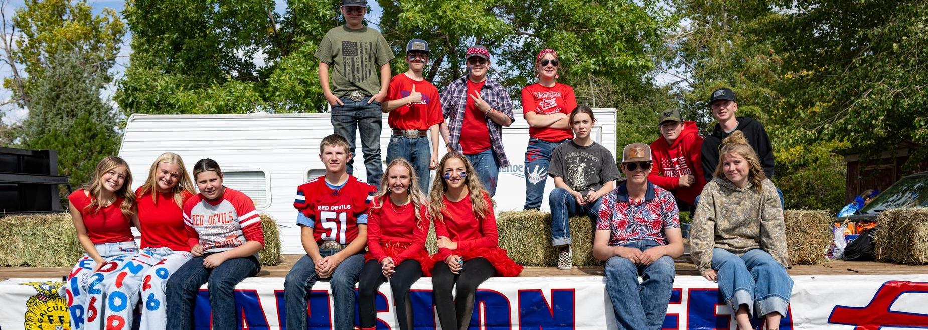 Students sitting on a float during a parade, wearing school colors.