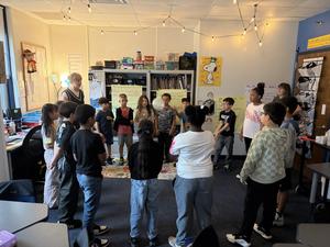 Student stand in a circle in a classroom.