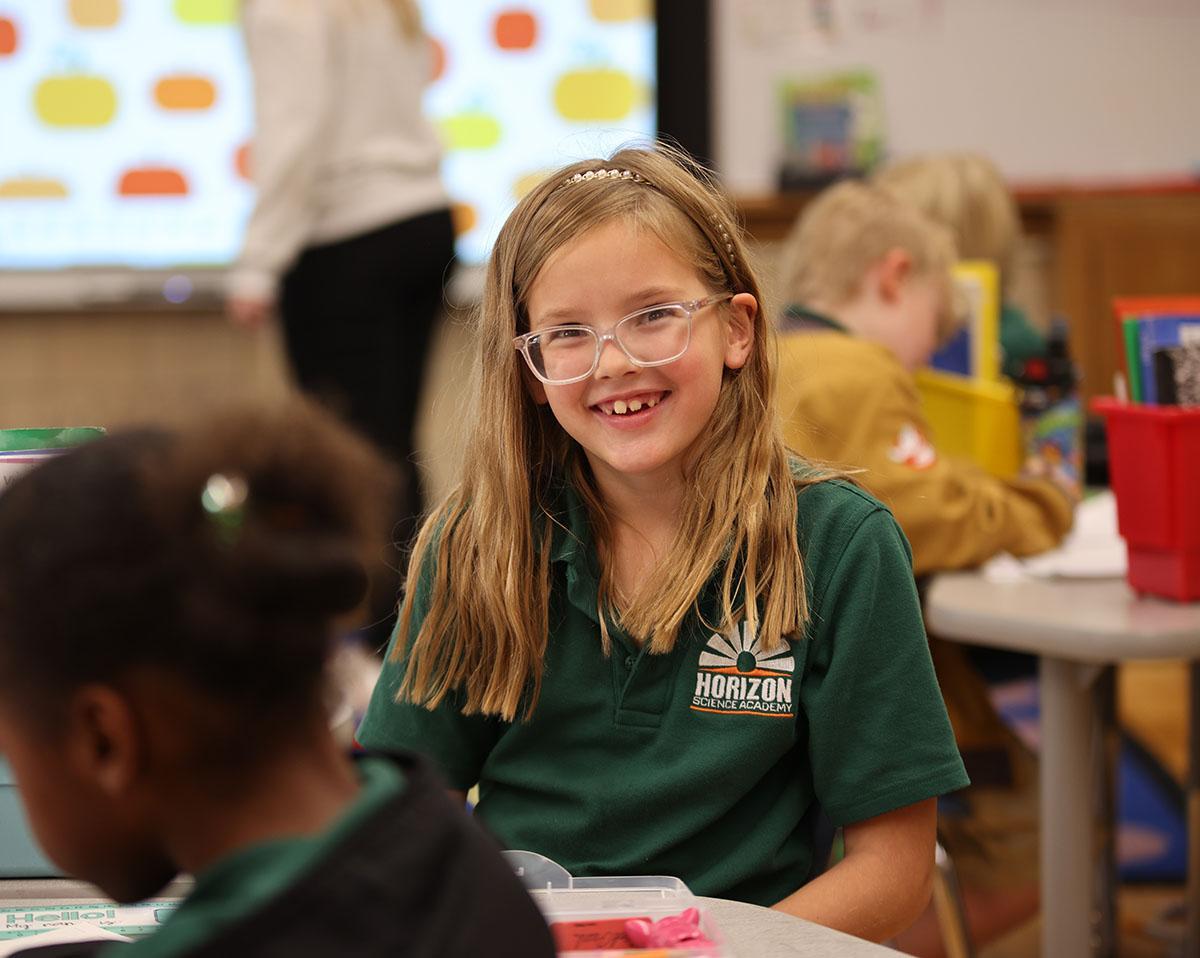 student in classroom smiling at camera