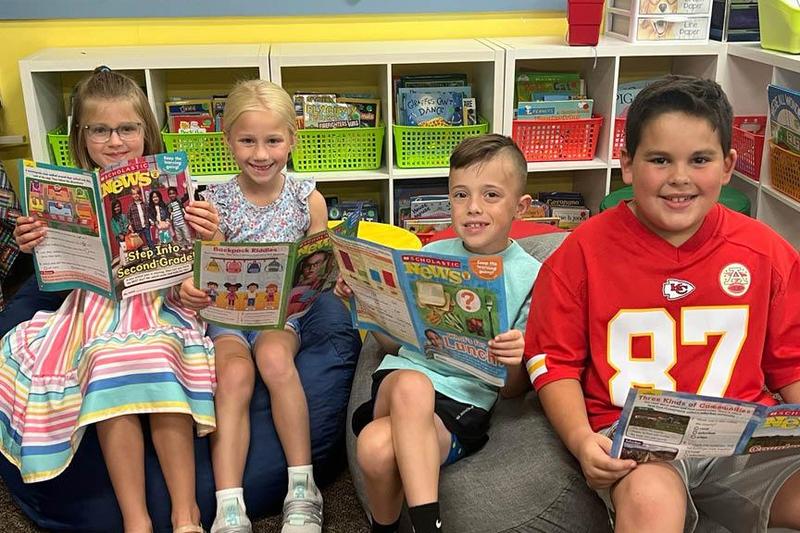 Katie Frescura, Lucie Kowalczuk, Carson Botti, and Ben Thoma sit on the new beanbags at Sunrise Elementary