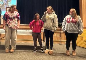 Four students talking to each other in front of a stage