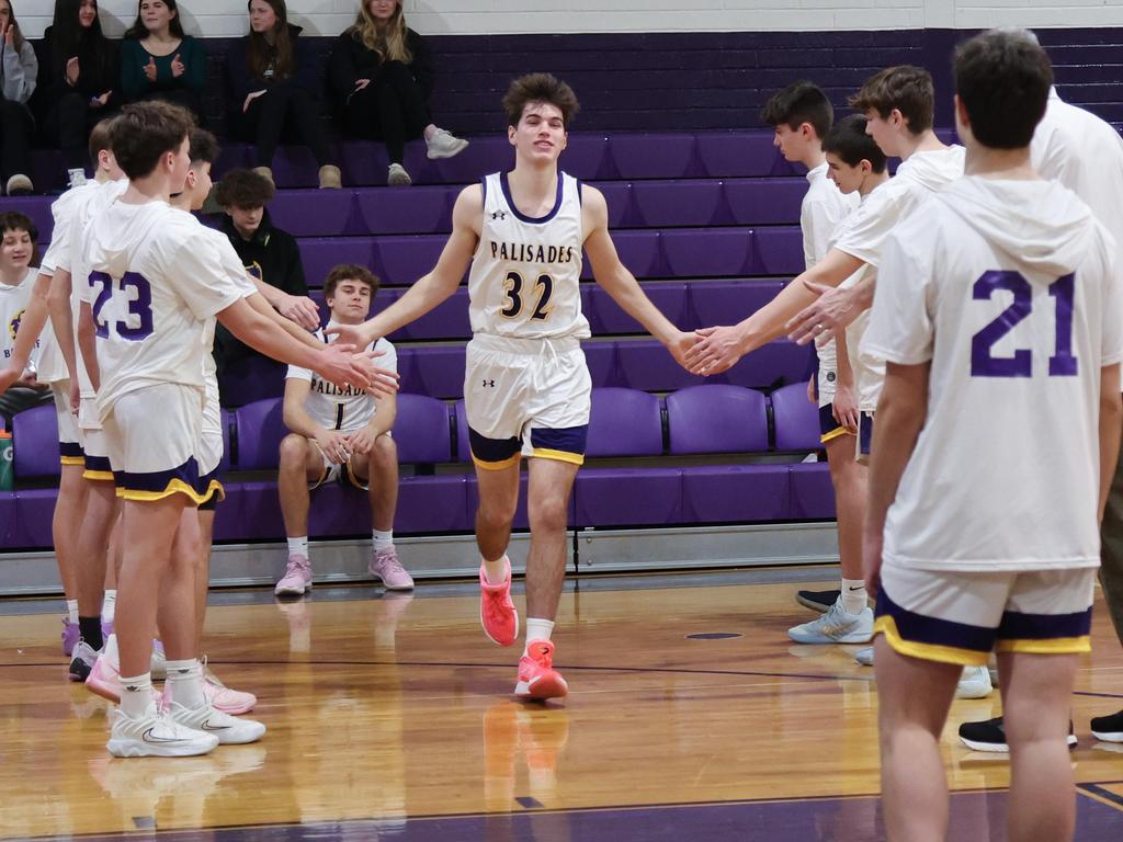 A basketball player being high fived on the court by team members.