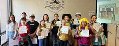 Group of students holding certificates in a school setting.