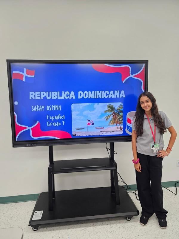 female student standing in front of project about Dominican Republic on a screen