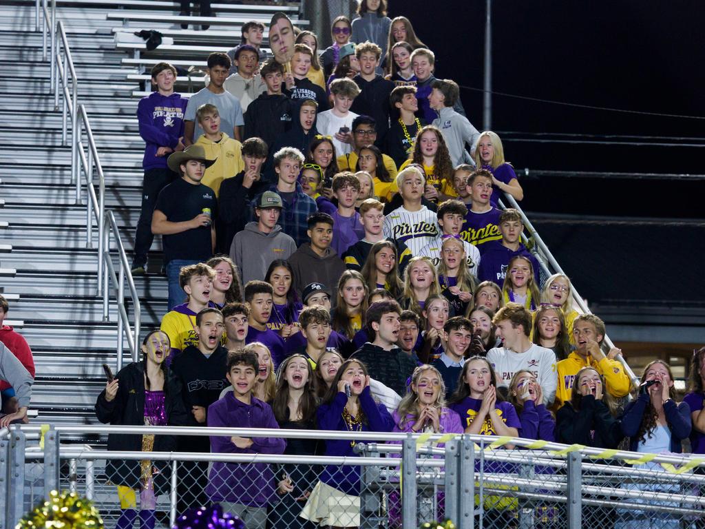 Students cheering in the bleachers during a footbal game.