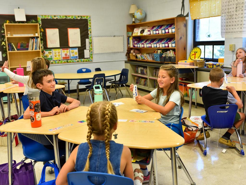 Students sitting at a table using flash cards for math.
