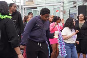 A group of young people dancing and celebrating in casual clothing at an outdoor event.