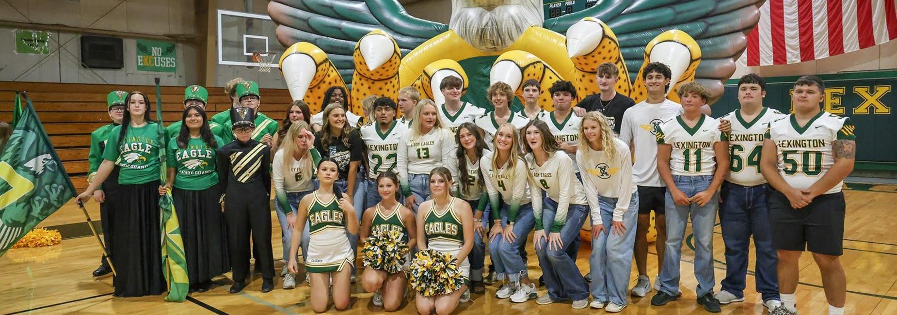 Large group of students in green and gold attire with cheering props.
