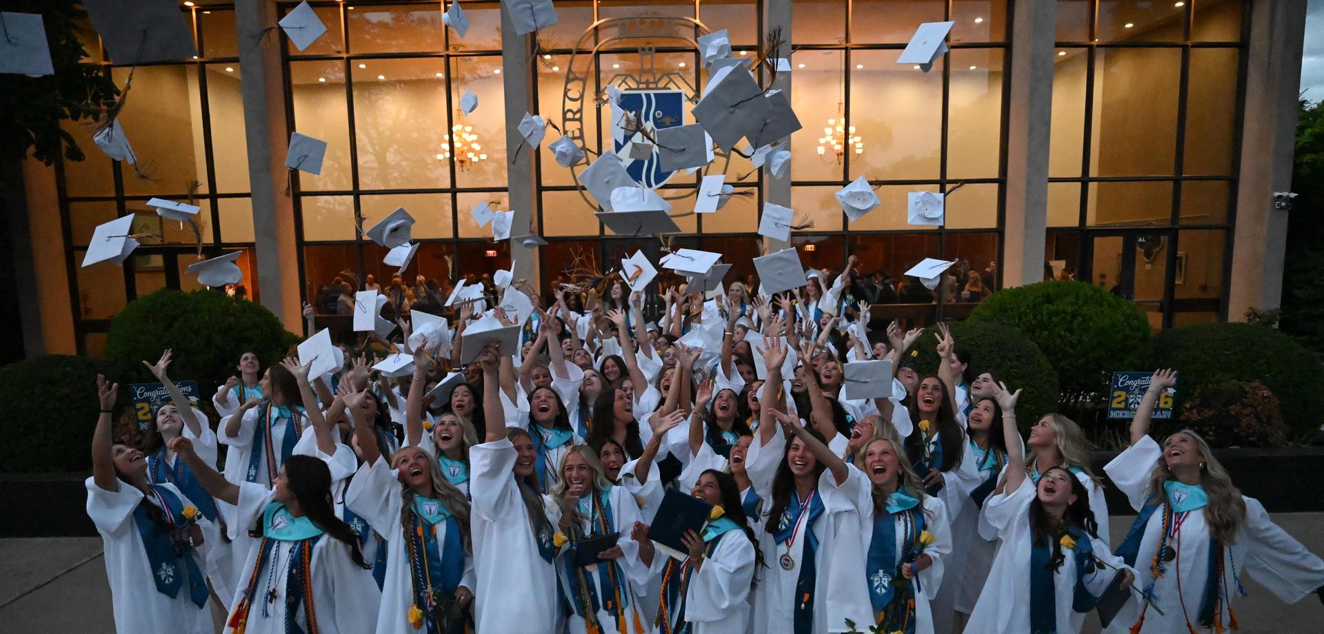 Graduates throwing caps in celebration outside a school building.