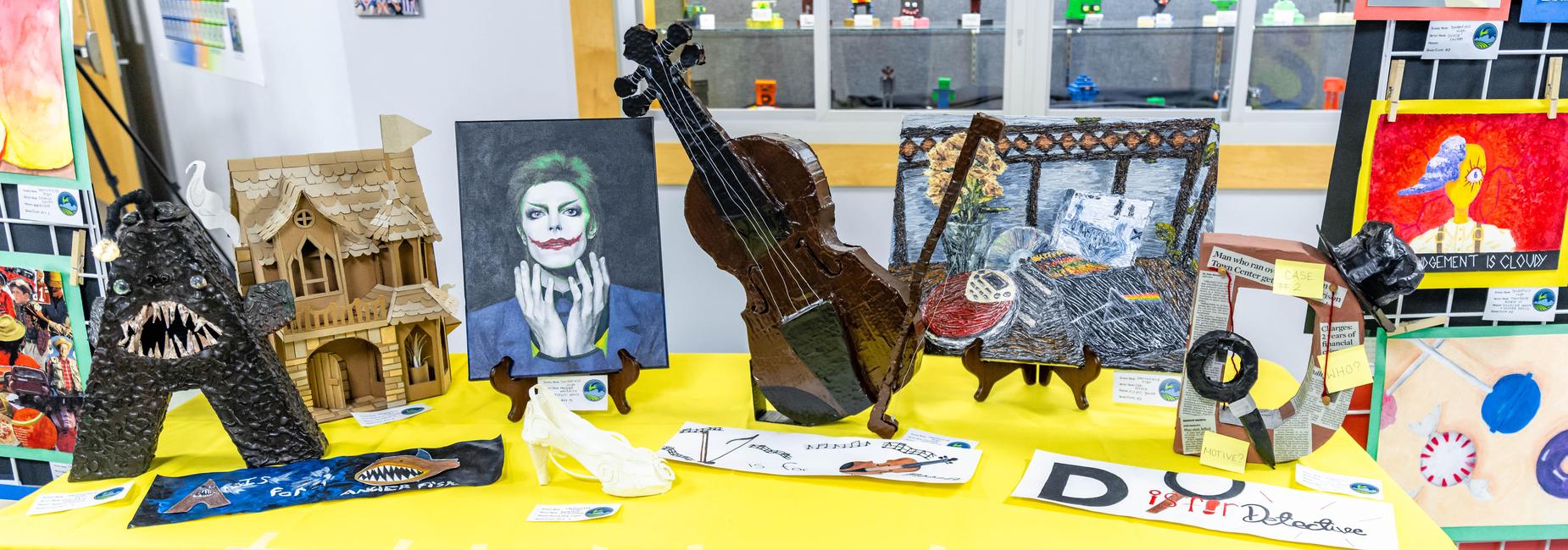 A table displaying various art pieces including a painting, a violin, and sculptures.