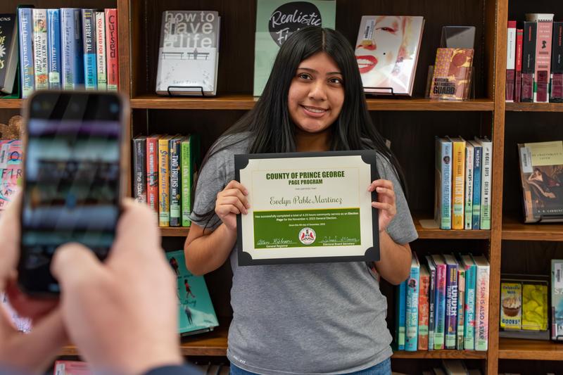 Evelyn Pablo Martinez smiles with her certificate after being recognized for participating in the Election Day Page Program