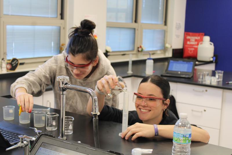 two girls with goggles filling beakers