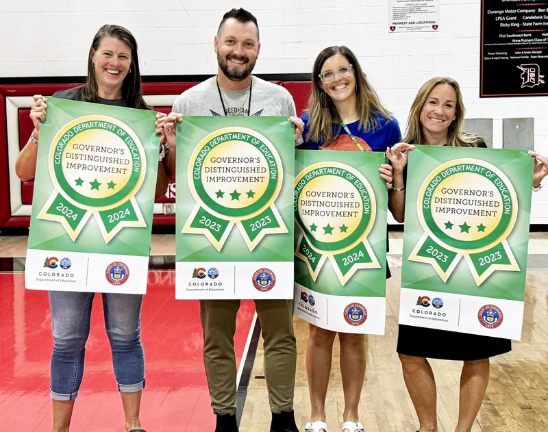 Four principals stand with banners indicating they earned CDE awards.
