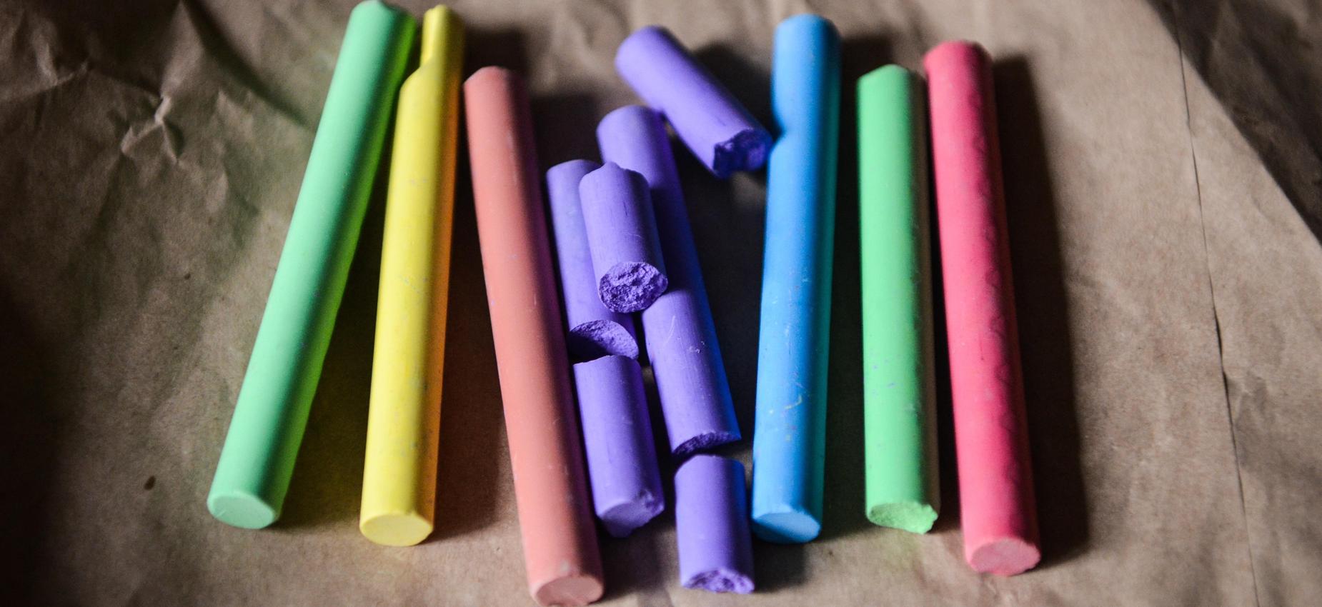 Colorful pieces of chalk arranged on a textured surface.