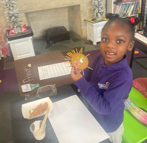 A scholar holds up her crafted turkey in class.