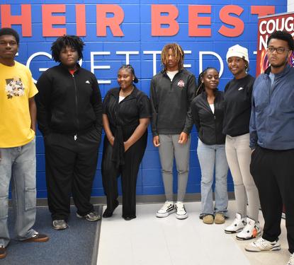 7 students standing in a school hallway.