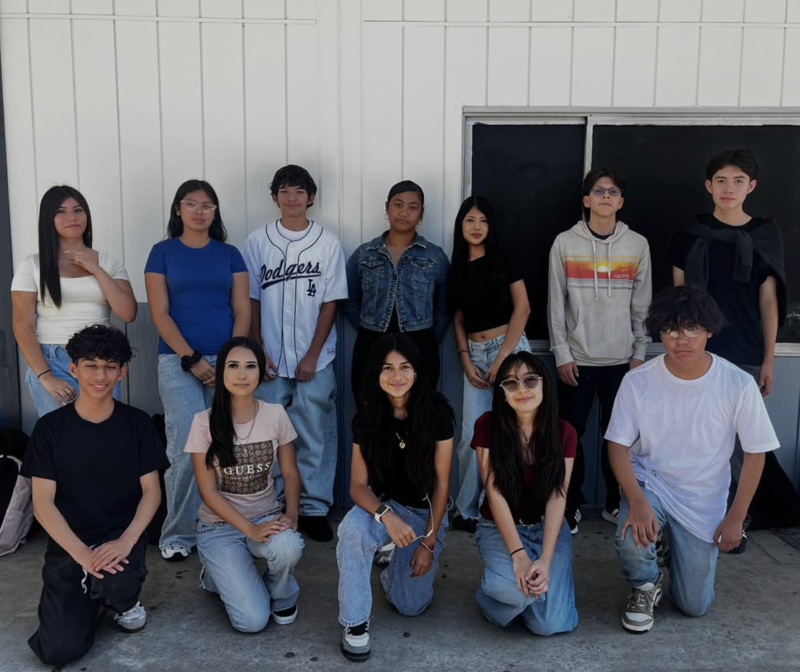 twelve students against a wall lined up in group photo