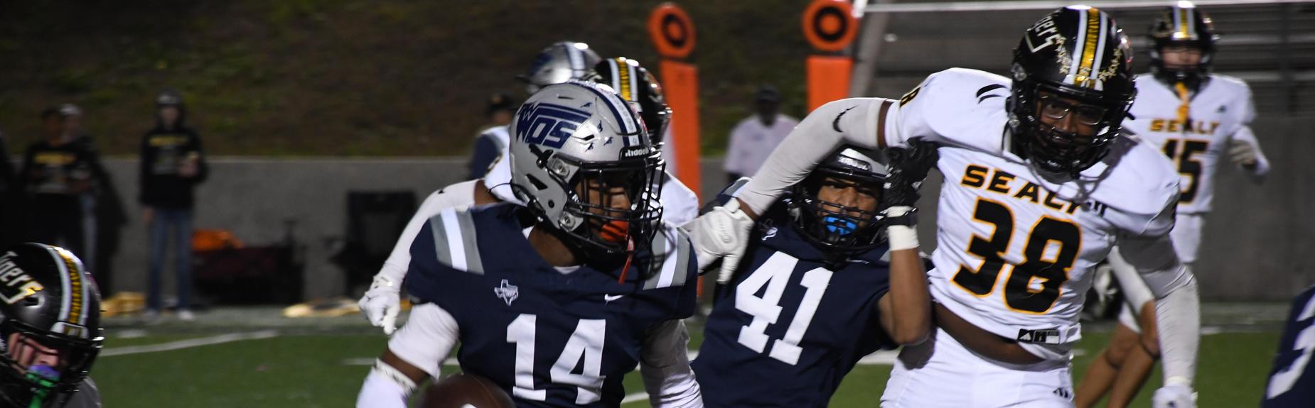 Football player evading defenders while running with the ball on the field.