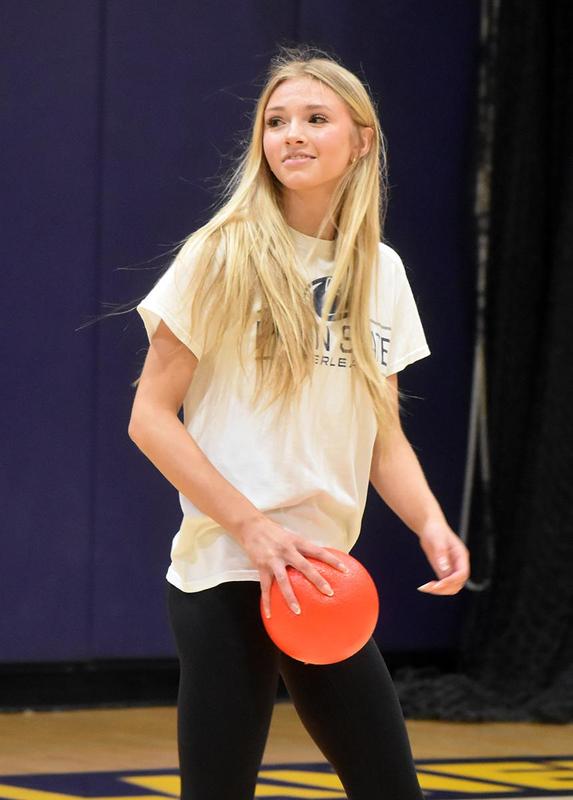 a girl in a white shirt holding a red ball