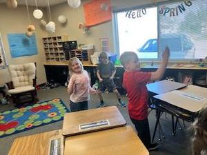 Students smiling and dancing in a bright classroom with decorations.
