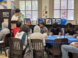 A group of students converses around a table decorated with blue and festive items.