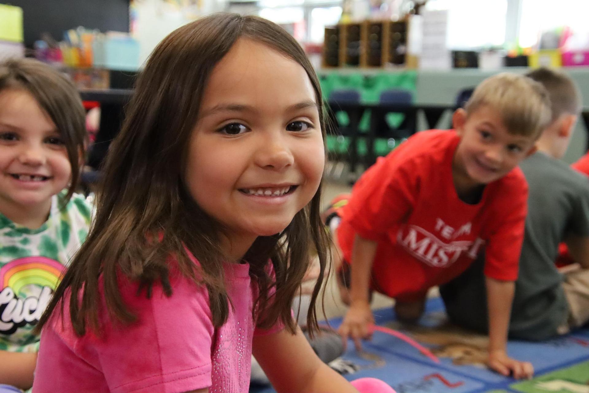elementary school girl smiling for the camera in a classroom