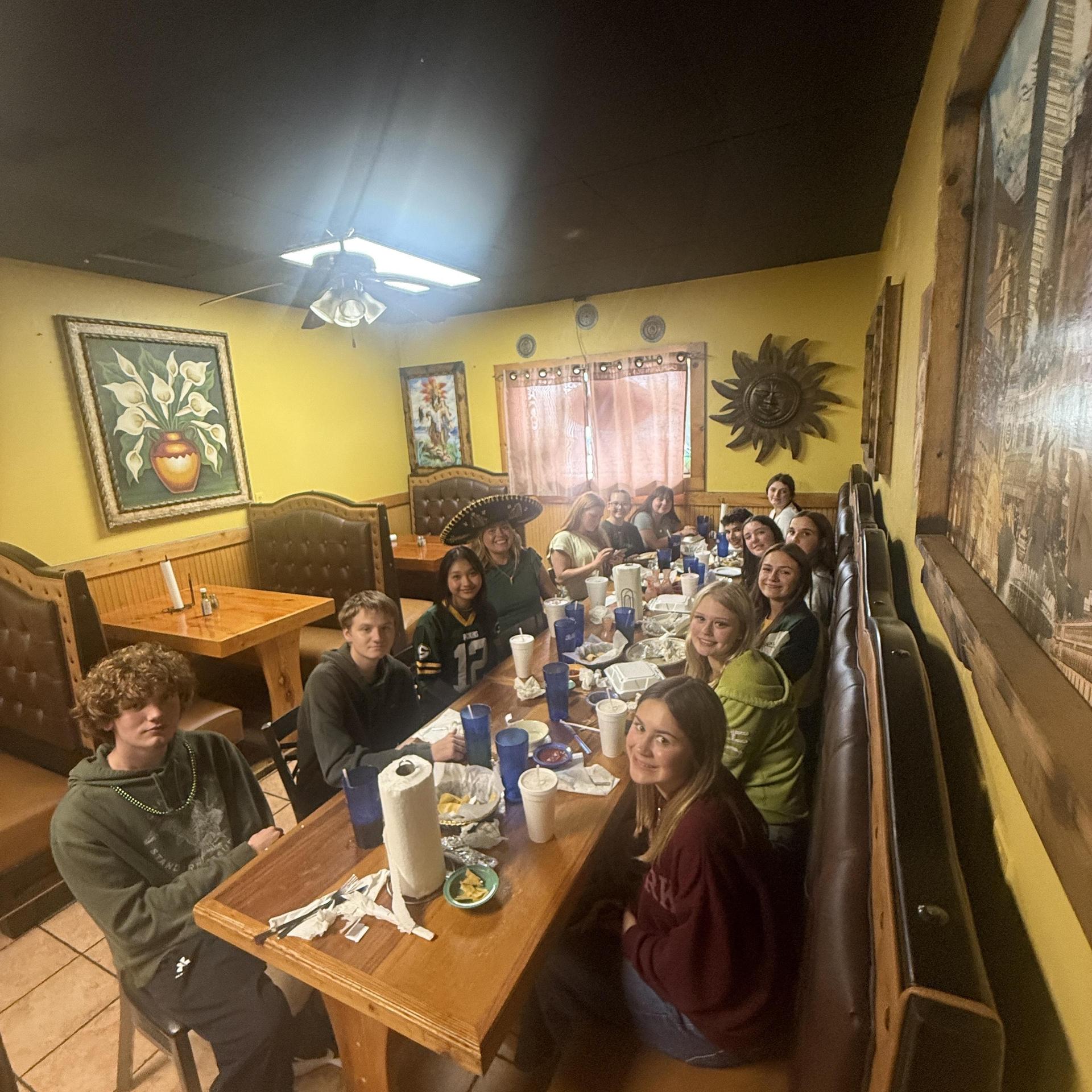 Group of friends dining together at a restaurant with food and drinks on the table.