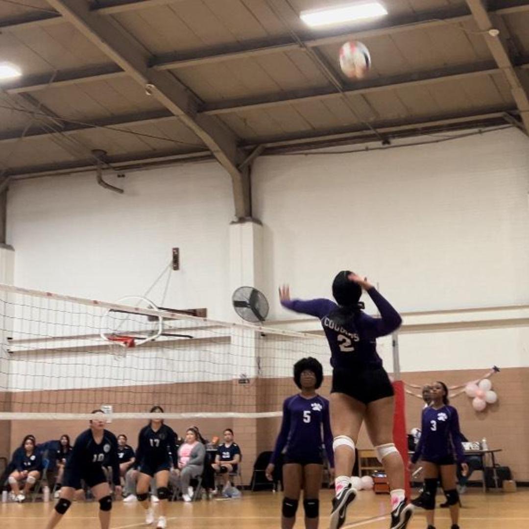 Player jumping to hit a volleyball in a gymnasium