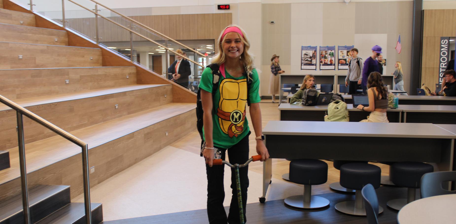 Girl dressed in Ninja Turtle shirt with scooter.