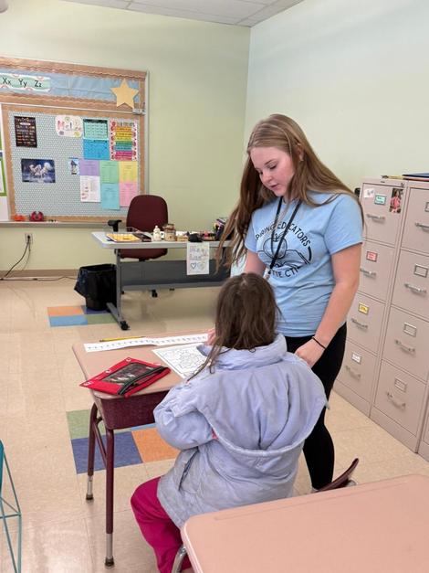 A student receives assistance from a teacher in a classroom setting.