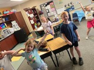 Children joyfully posing and dancing in a classroom.