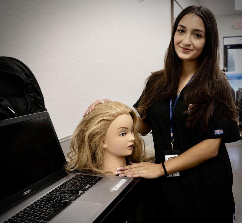 Female student standing next to a cosmetology manikin