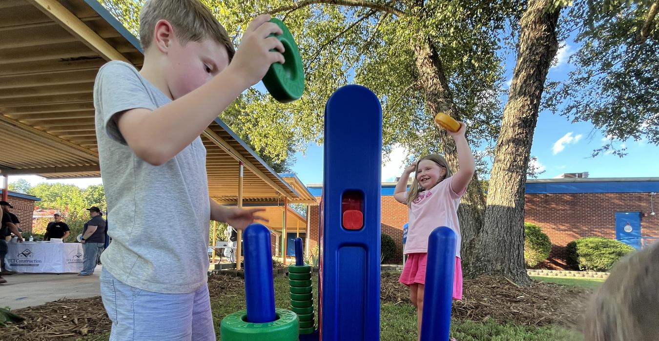 Children playing with a stacking toy outdoors.