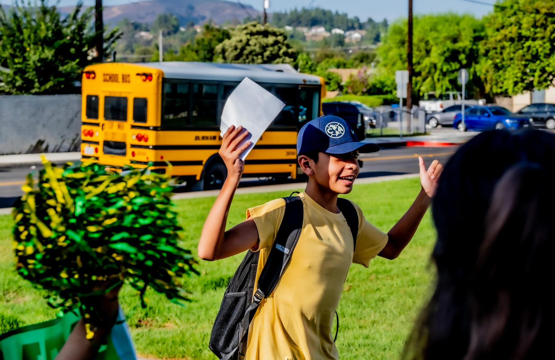 student is cheered and raises arms waring a yellow shirt