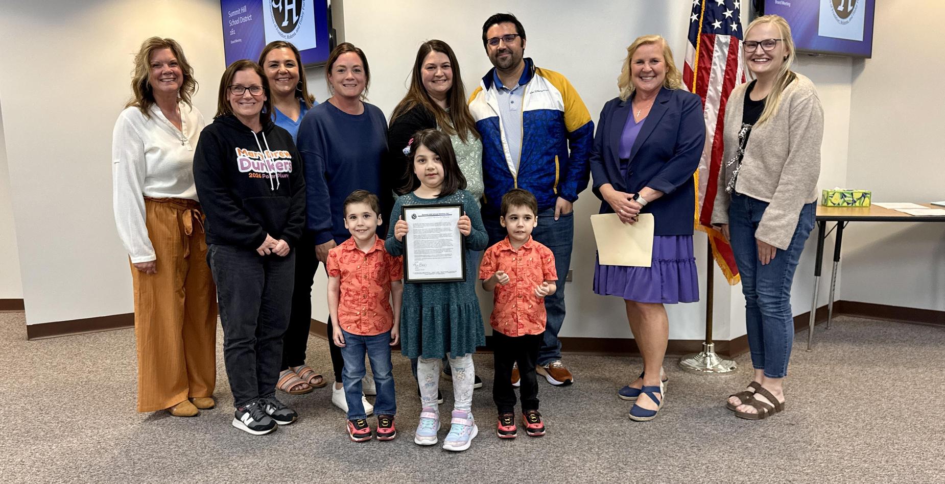Group photo of the Dr. Julian Rogus School Kindergarten Exemplary Student pictured with her family and several Summit Hill 161 staff members after being recognized during the May Board of Education meeting.