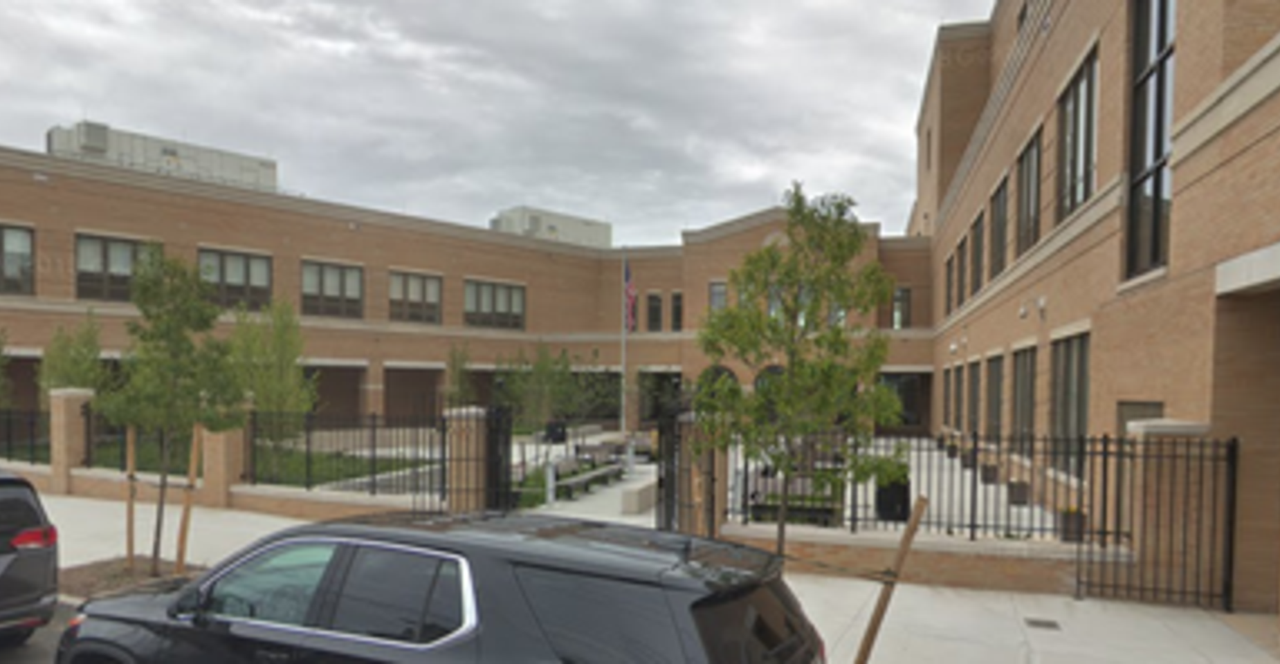 A school building with brick walls, trees, and a courtyard.