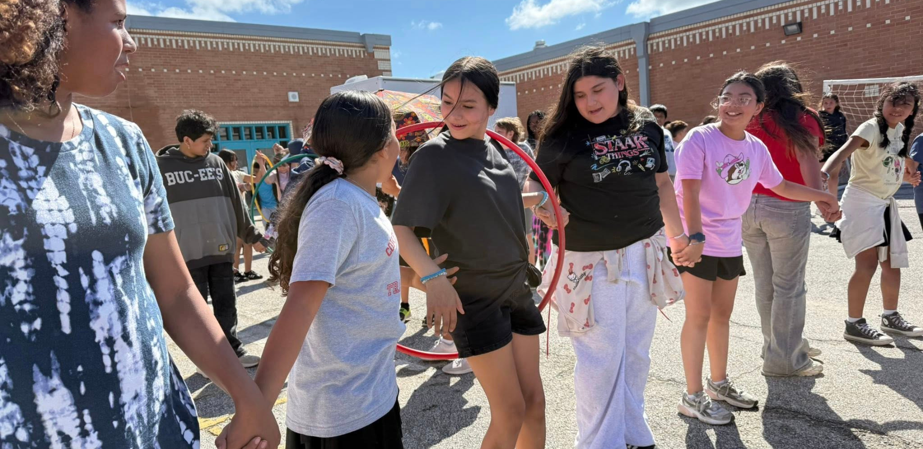 girls holding hands to play hoola hoop game
