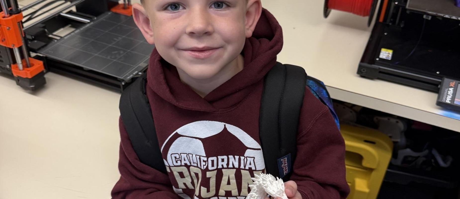 3D print club student holding the white dragon he printed