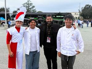 Three male students and their music director smile at the camera after their tournament of roses participation.