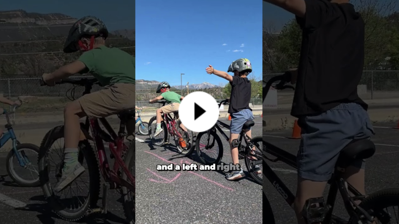 2nd graders practice a left-turn hand signal while riding bikes on a safety course