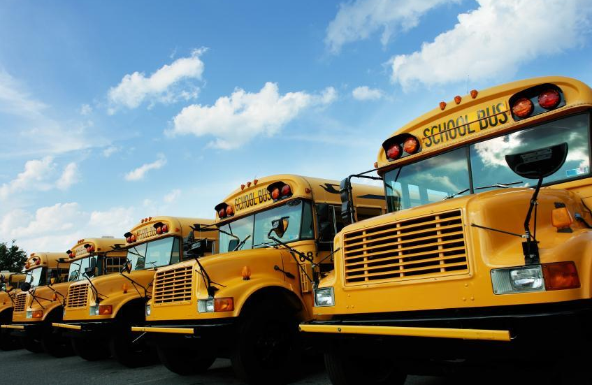 Five yellow school busses parked next to each other