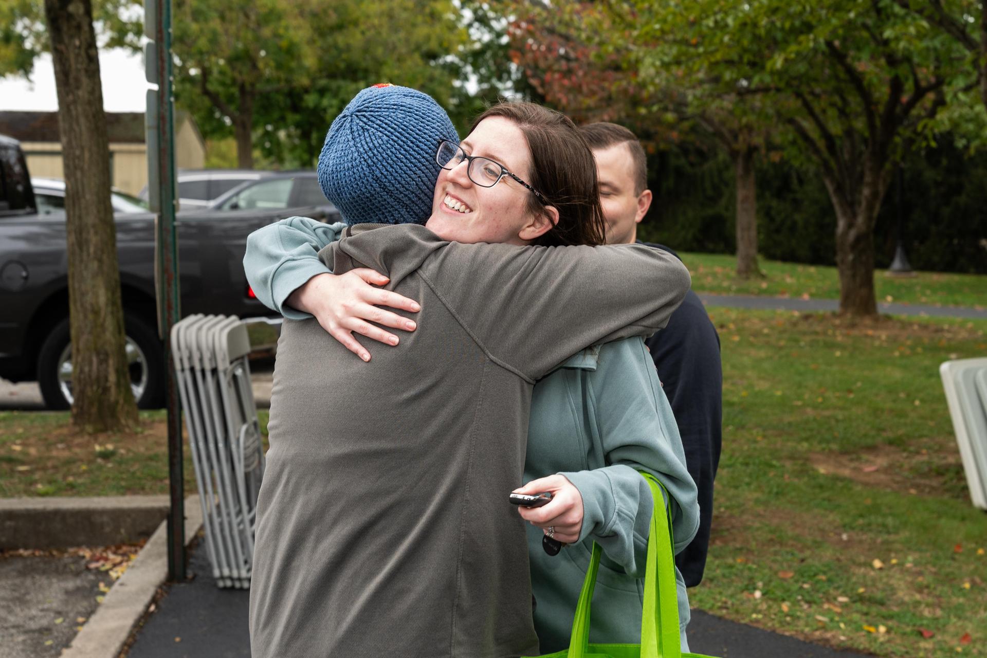 Two women hugging outside at event.