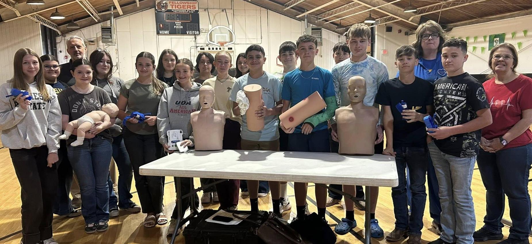 Group of students posing with mannequins for a safety training session.