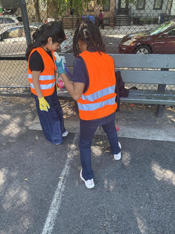 A pair of students working together to sweep up trash