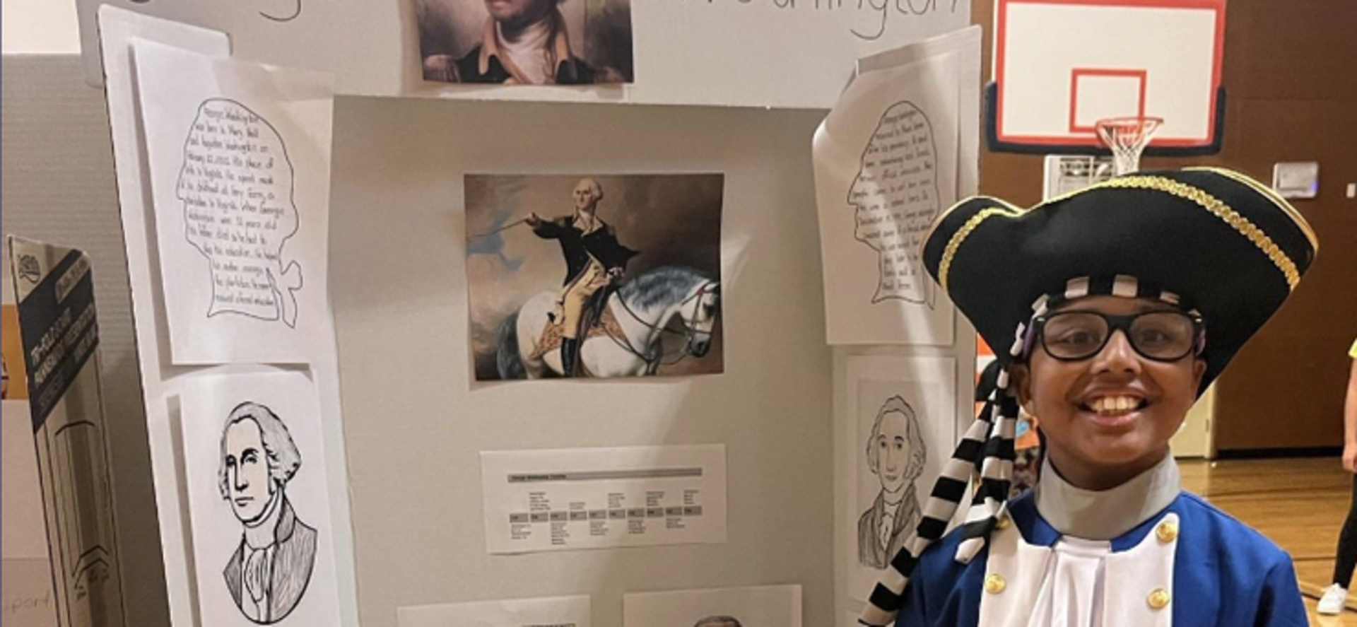 A child in costume represents George Washington at a school project display.