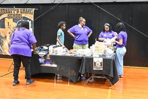 Group of people at a black table with various items for sale.
