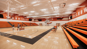 Architectural rendering of the proposed new gymnasium, showing the basketball court, bleachers, and spectator seating.