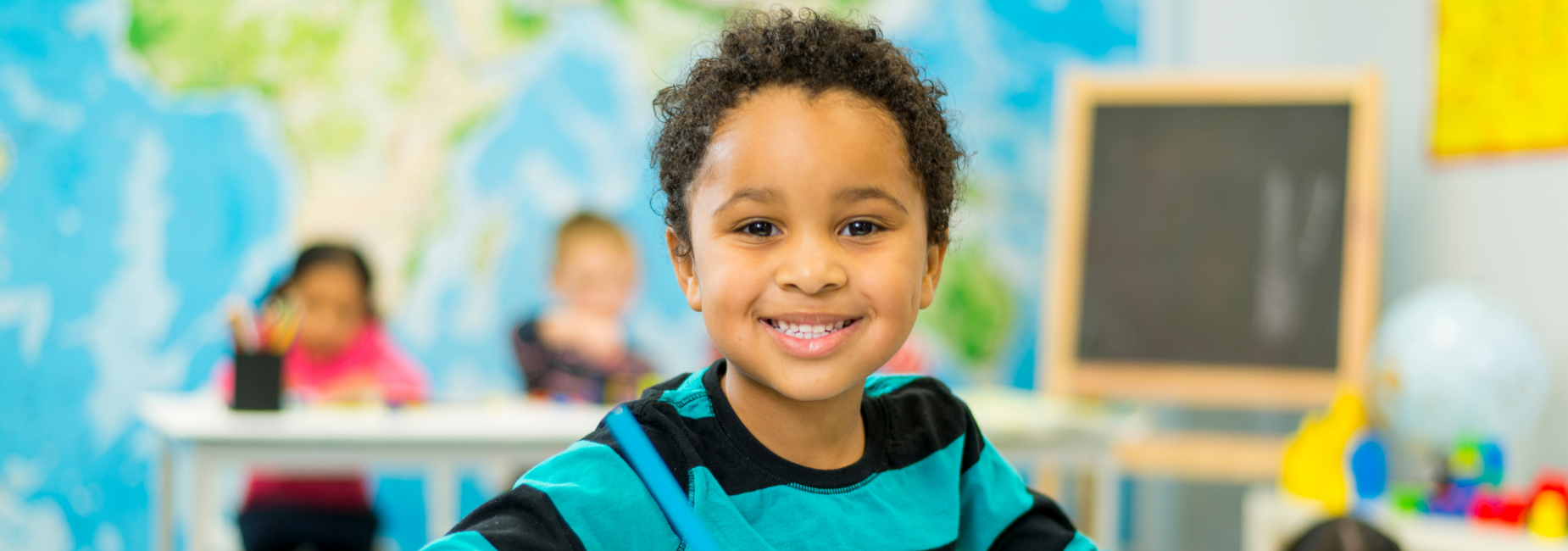 kindergarten student smiling at her table in the classroom