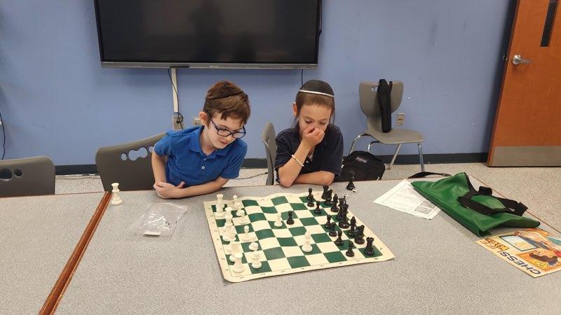 2 boys contemplate a chess board